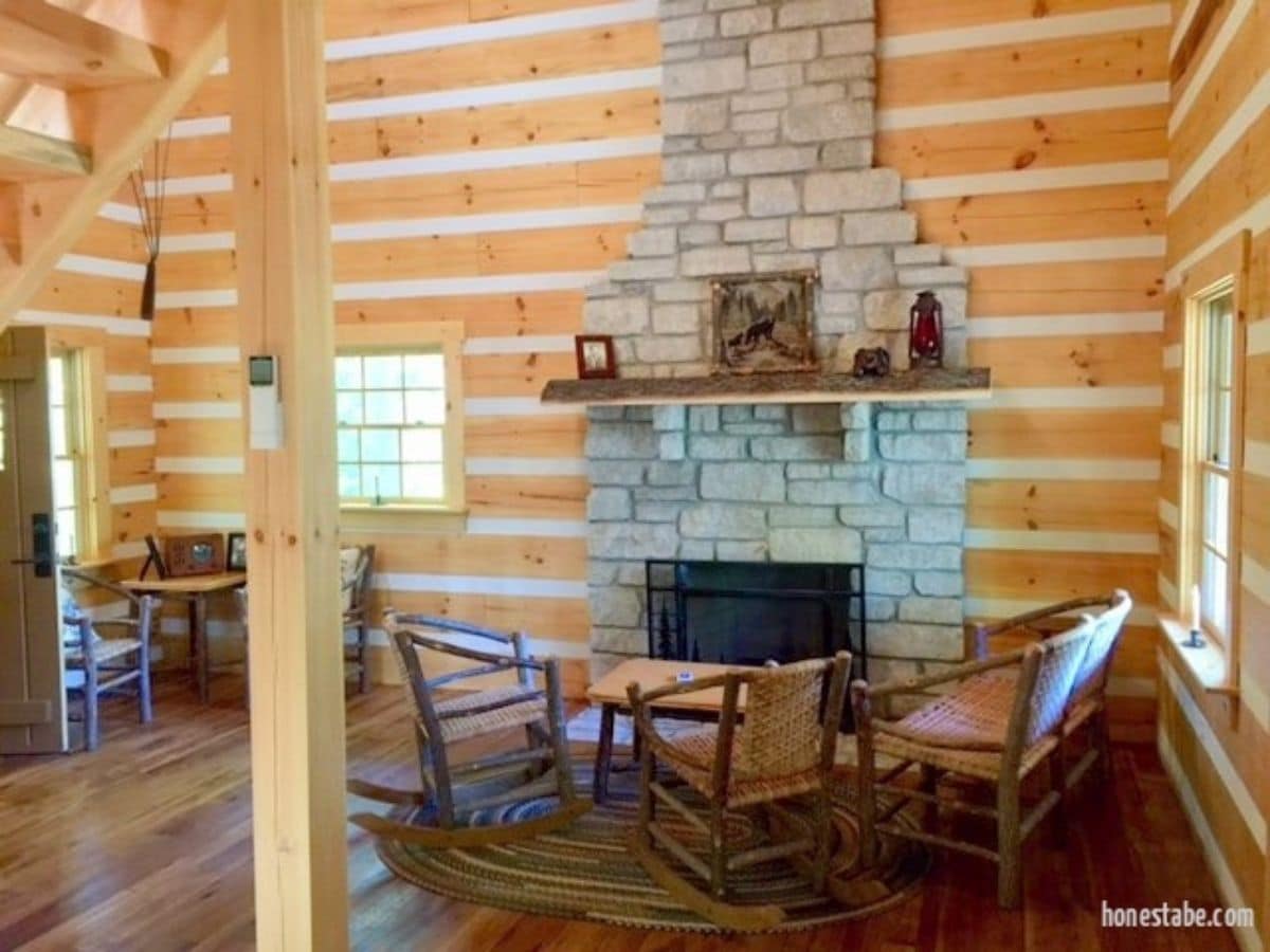 stone fireplace against wood wall with rocking chairs in front