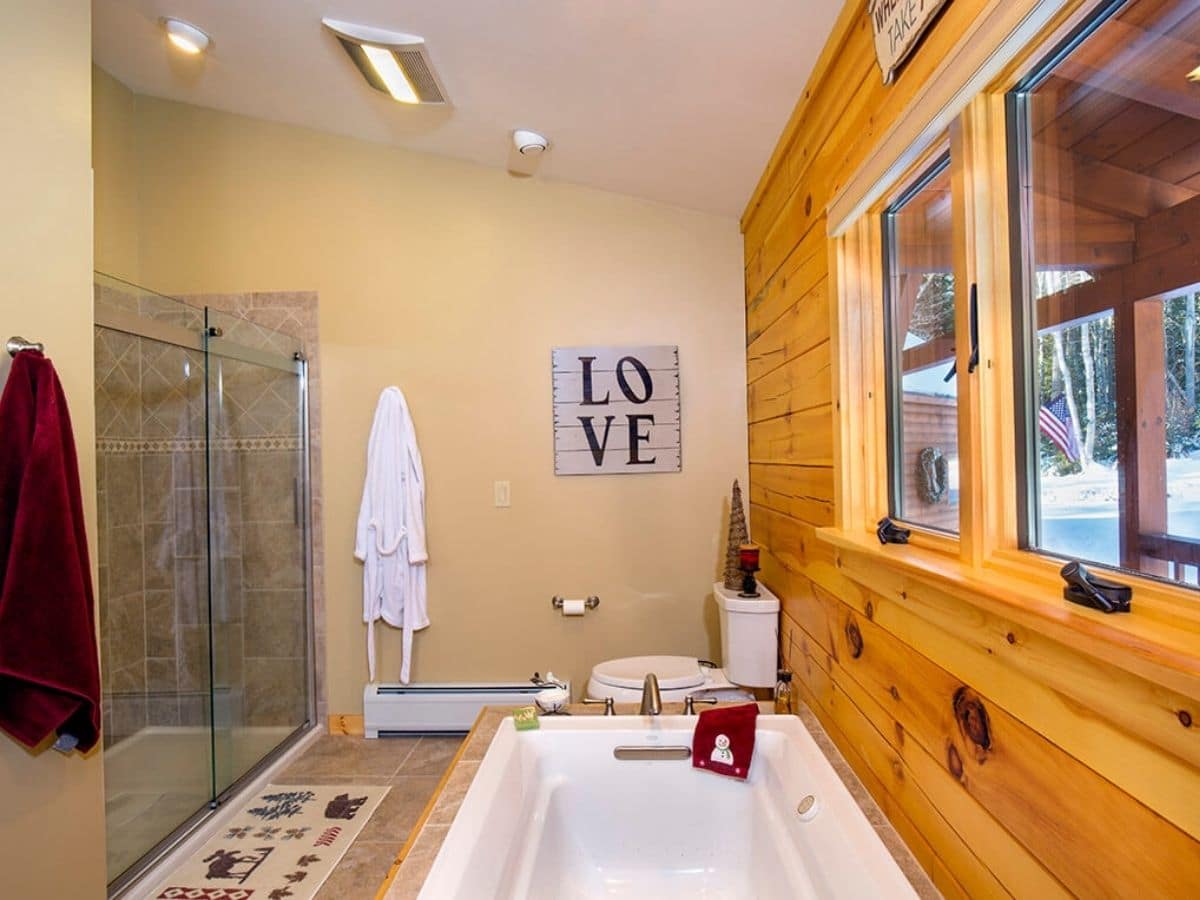 love sign against cream wall in bathroom with sink in foreground and shower with tile on the far left