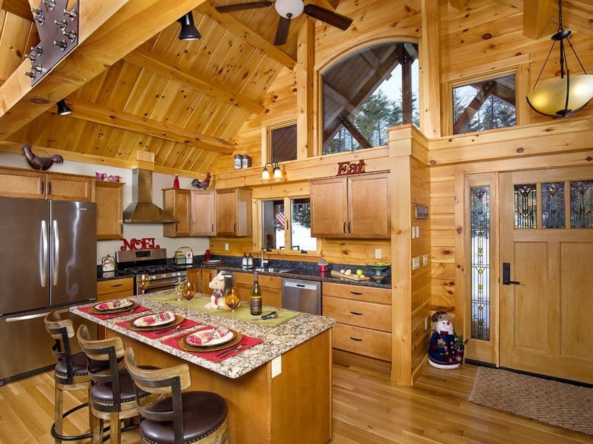 log cabin kitchen with door leading outside on far right and island bar on front left