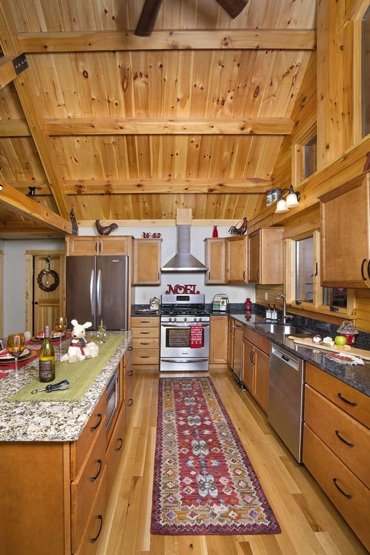 view down kitchen with stove against back wall and island to left with side counters and dishwasher on right