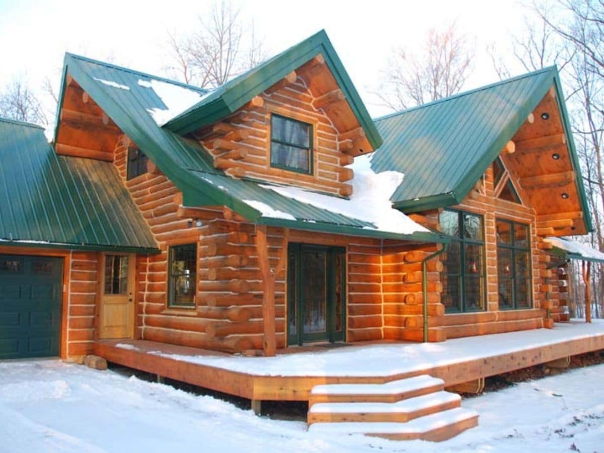 Front door and porch on log cabin with green roof