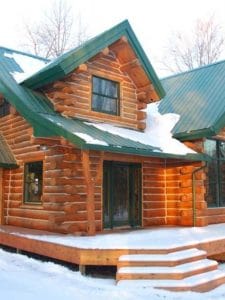 Dark wood log cabin front door with green roof