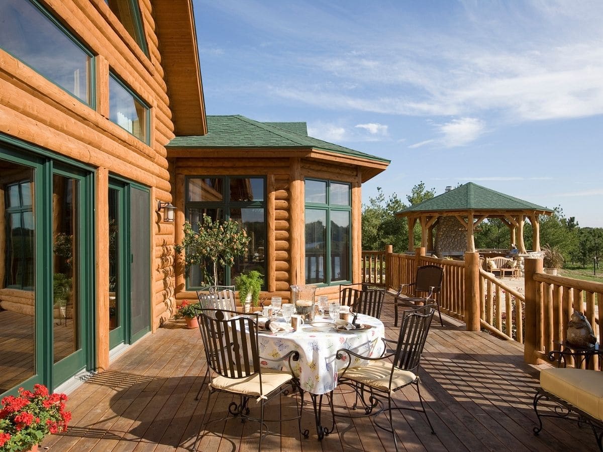 back deck of log cabin with metal bistor set against railing