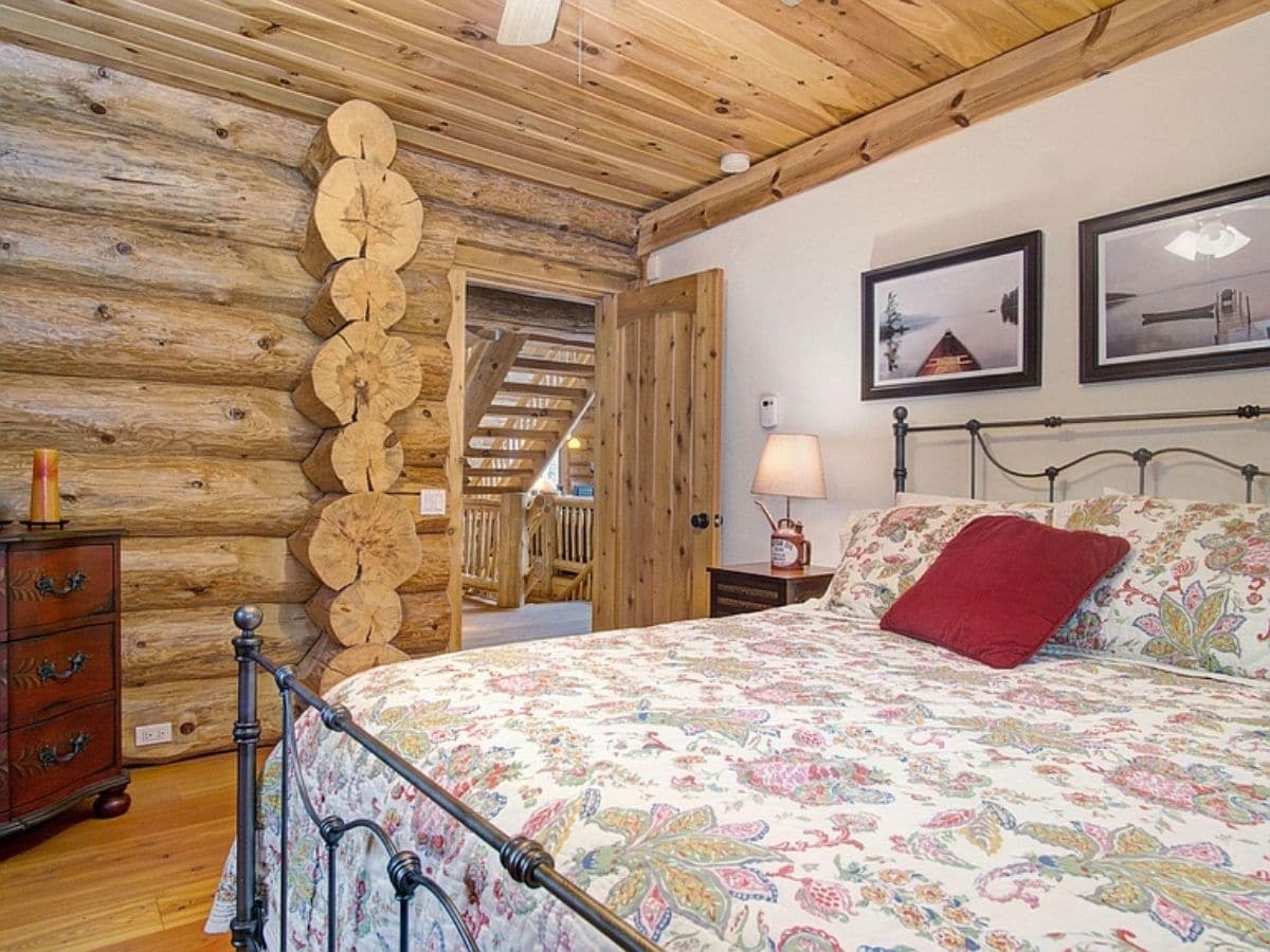 bed with black iron bedframe next to log home
