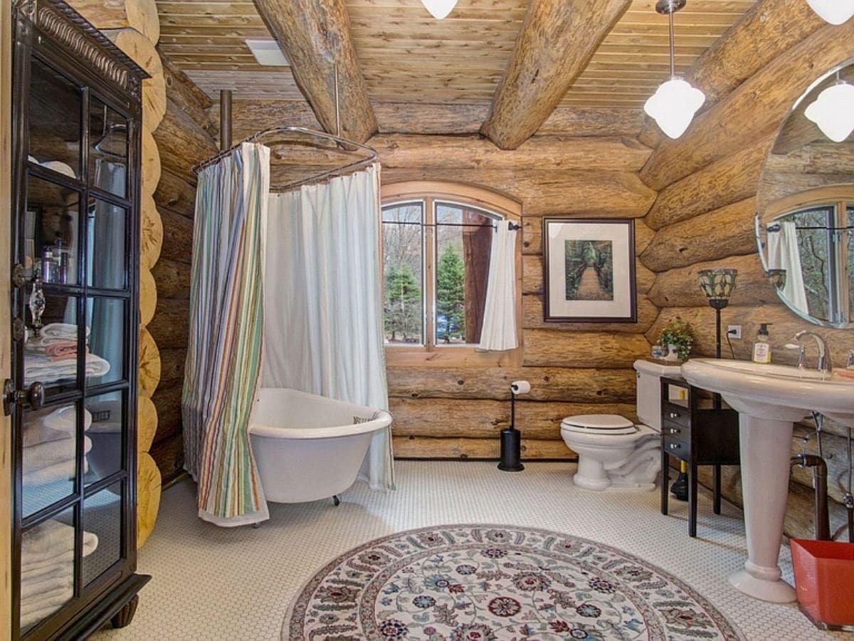 white clawfoot tub with shower curtain in corner of log bathroom