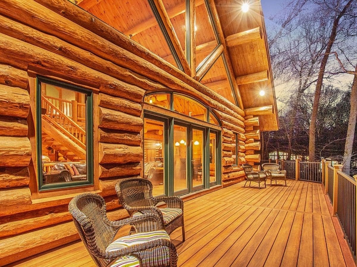 deck on back of log cabin with green trim around windows
