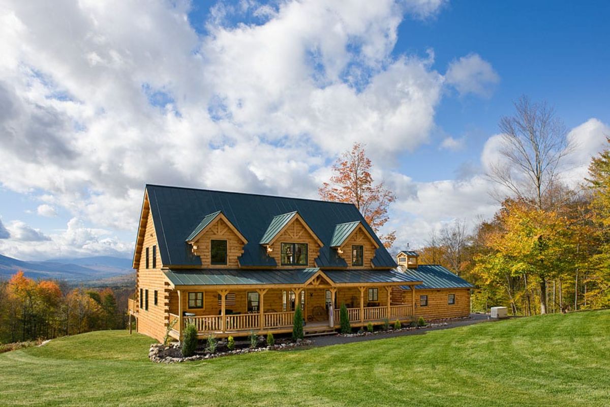 light blonde log cabin on grassy hill with green roof