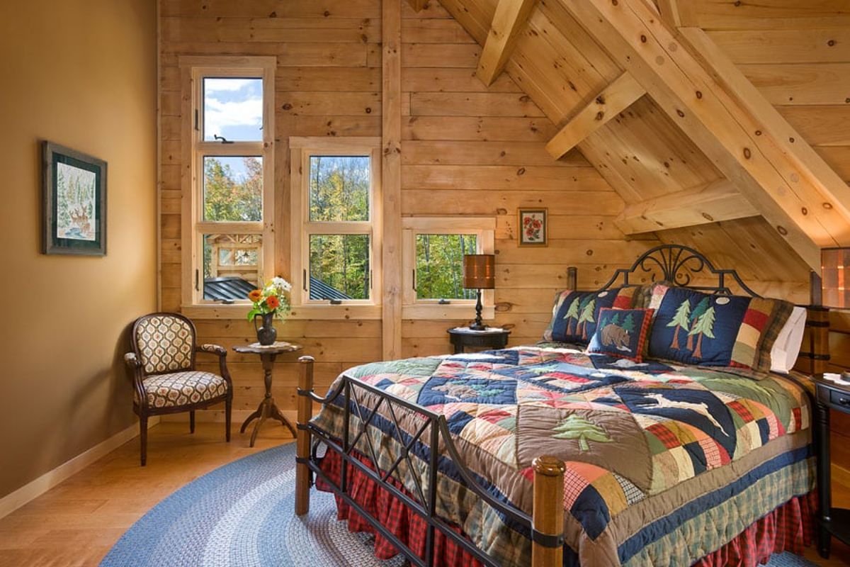 light wood walls in upstairs bedroom of log cabin with table under window