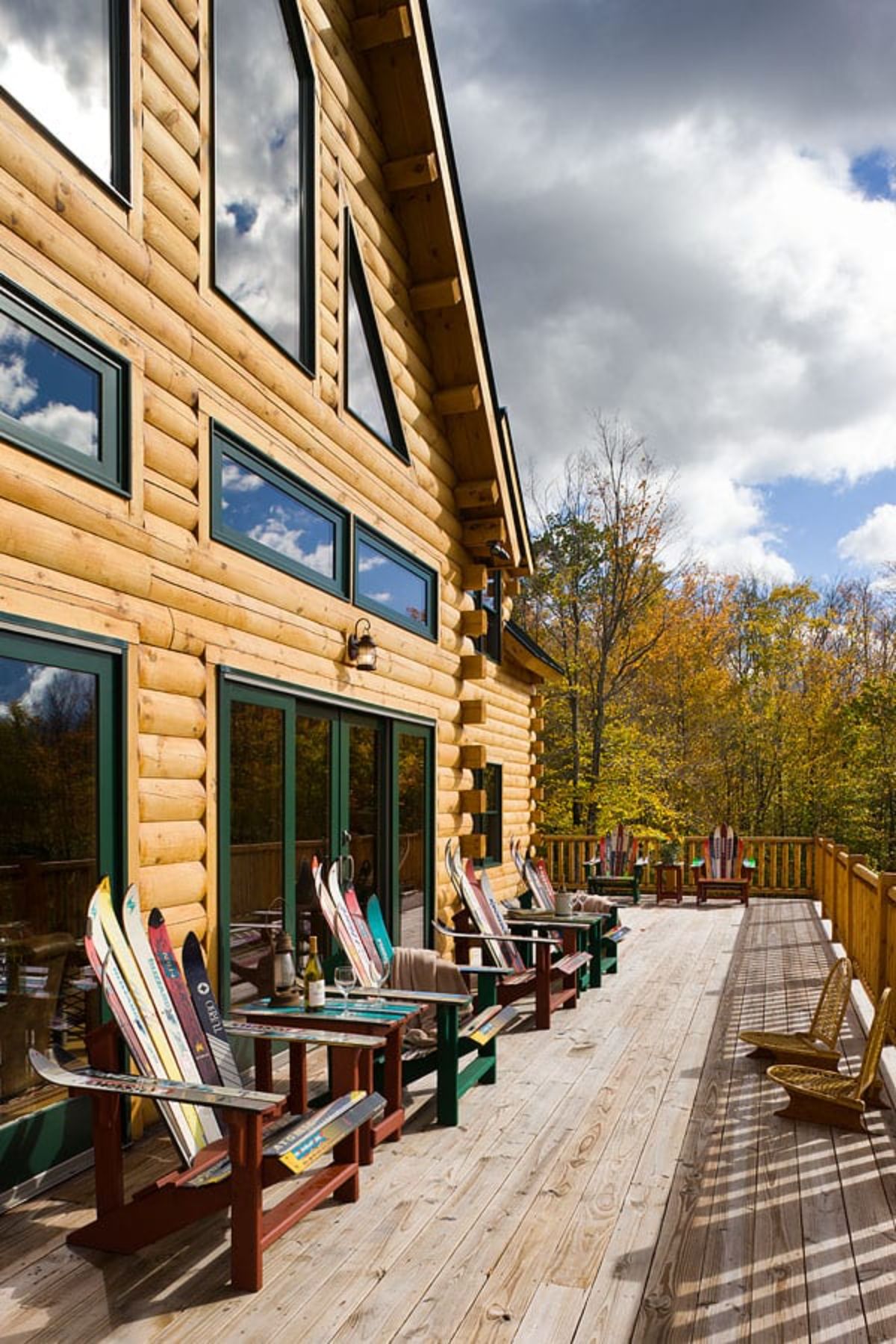 patio on back of log cabin with green and wood adirondack chairs