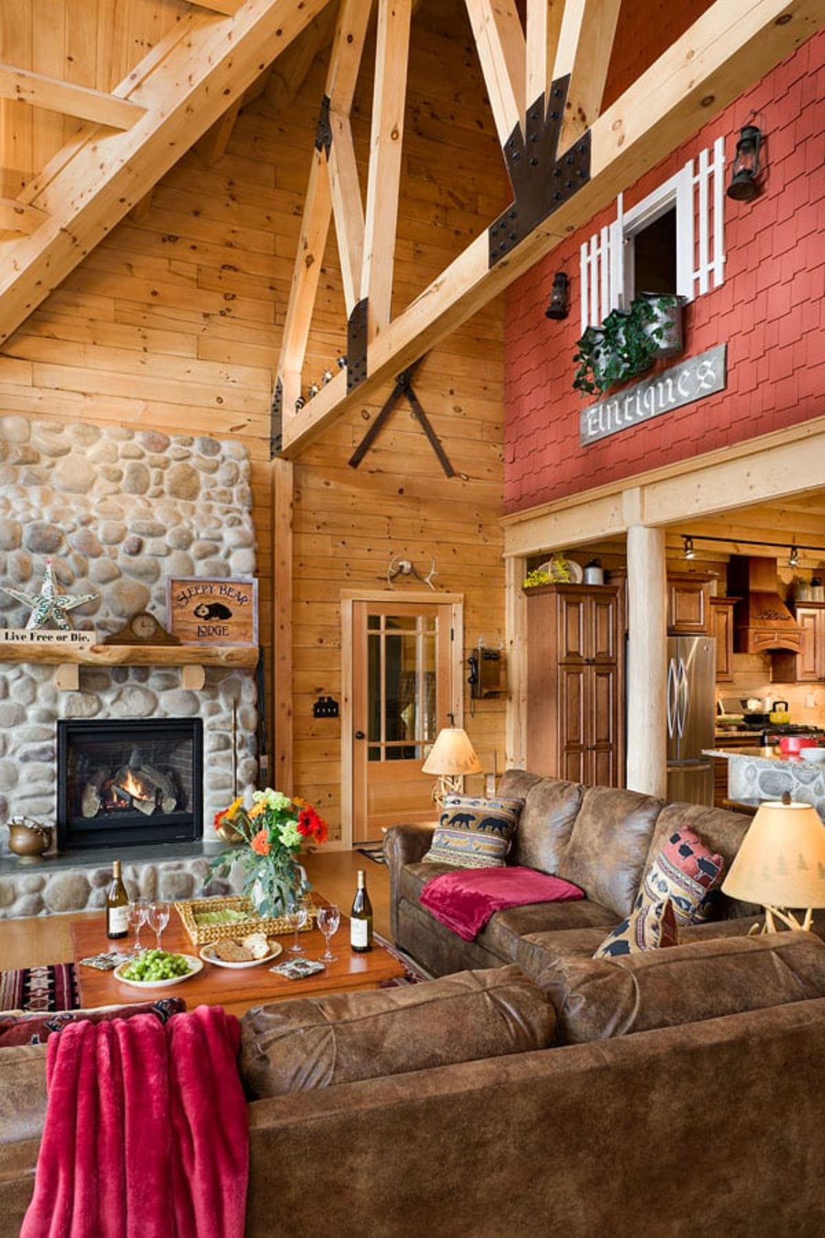 brown sofa with red blanket in front of stone fireplace