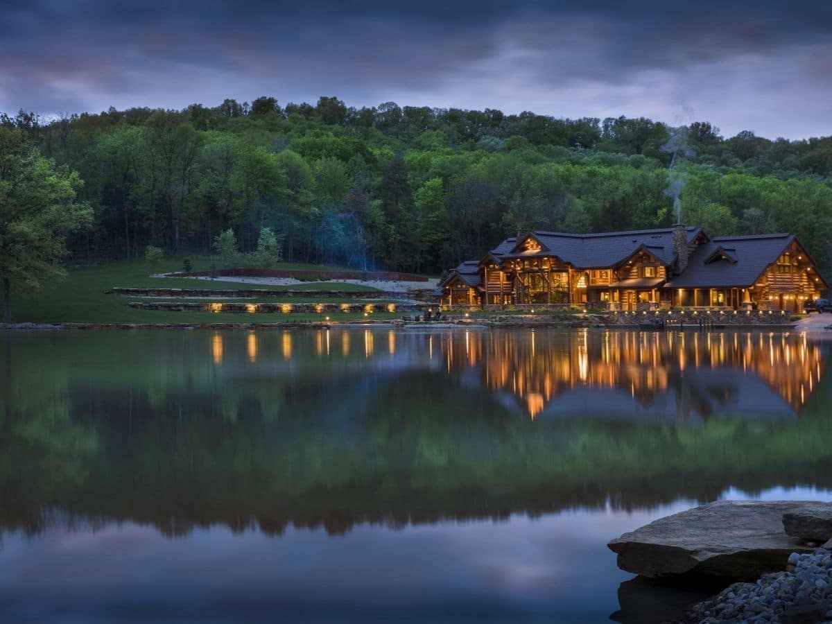 lake in foreground with log cabin in background against treeline