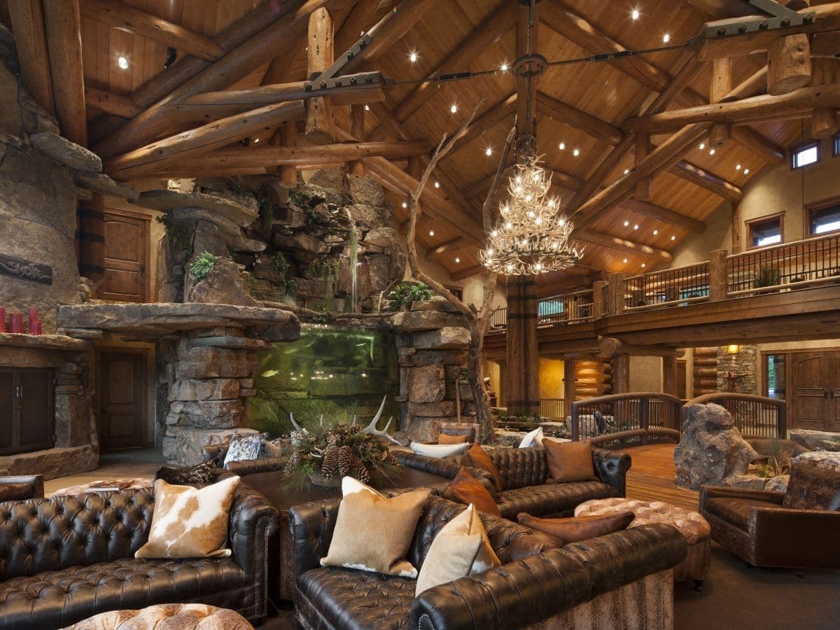 log cabin great room with dark sofas and large chandelier hanging over room