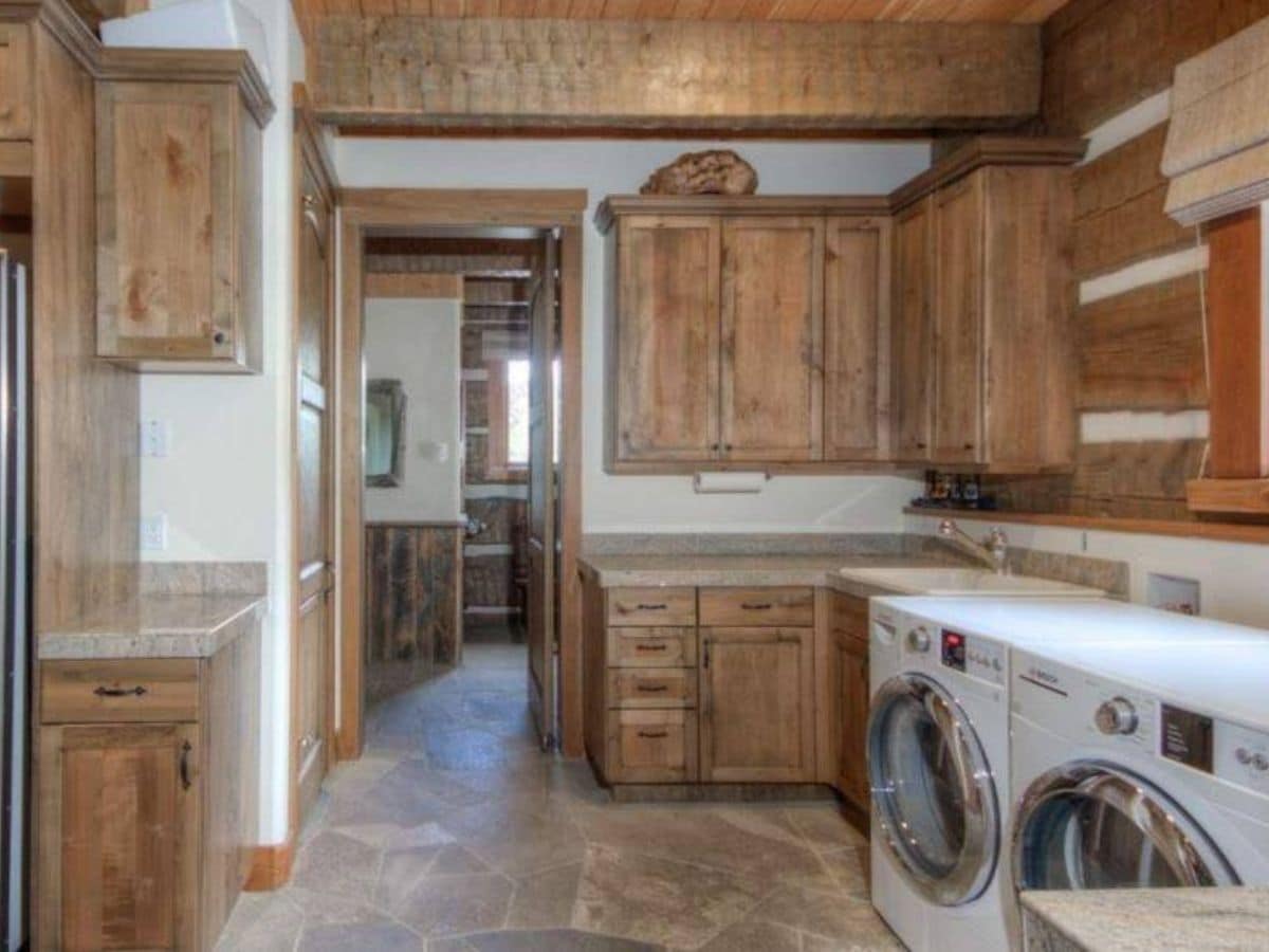 white washer and dryer against right wall underneath wood cabinets