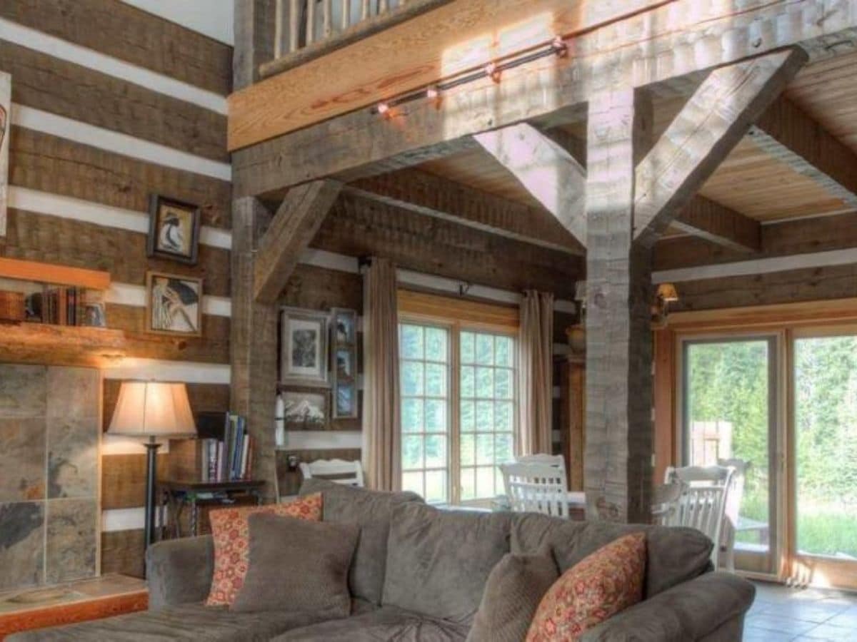 brown sofa underneath loft of log cabin second floor