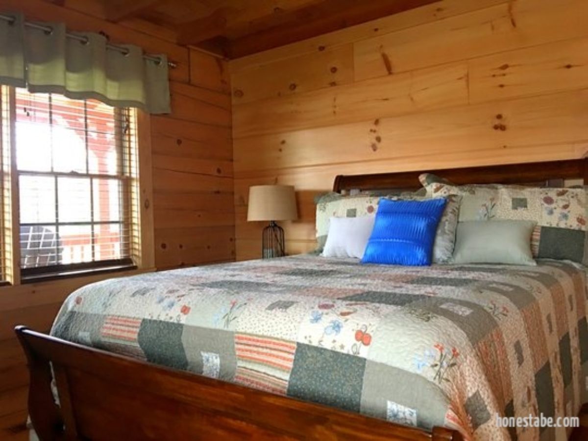 bed with quilt against wall of log cabin bedroom