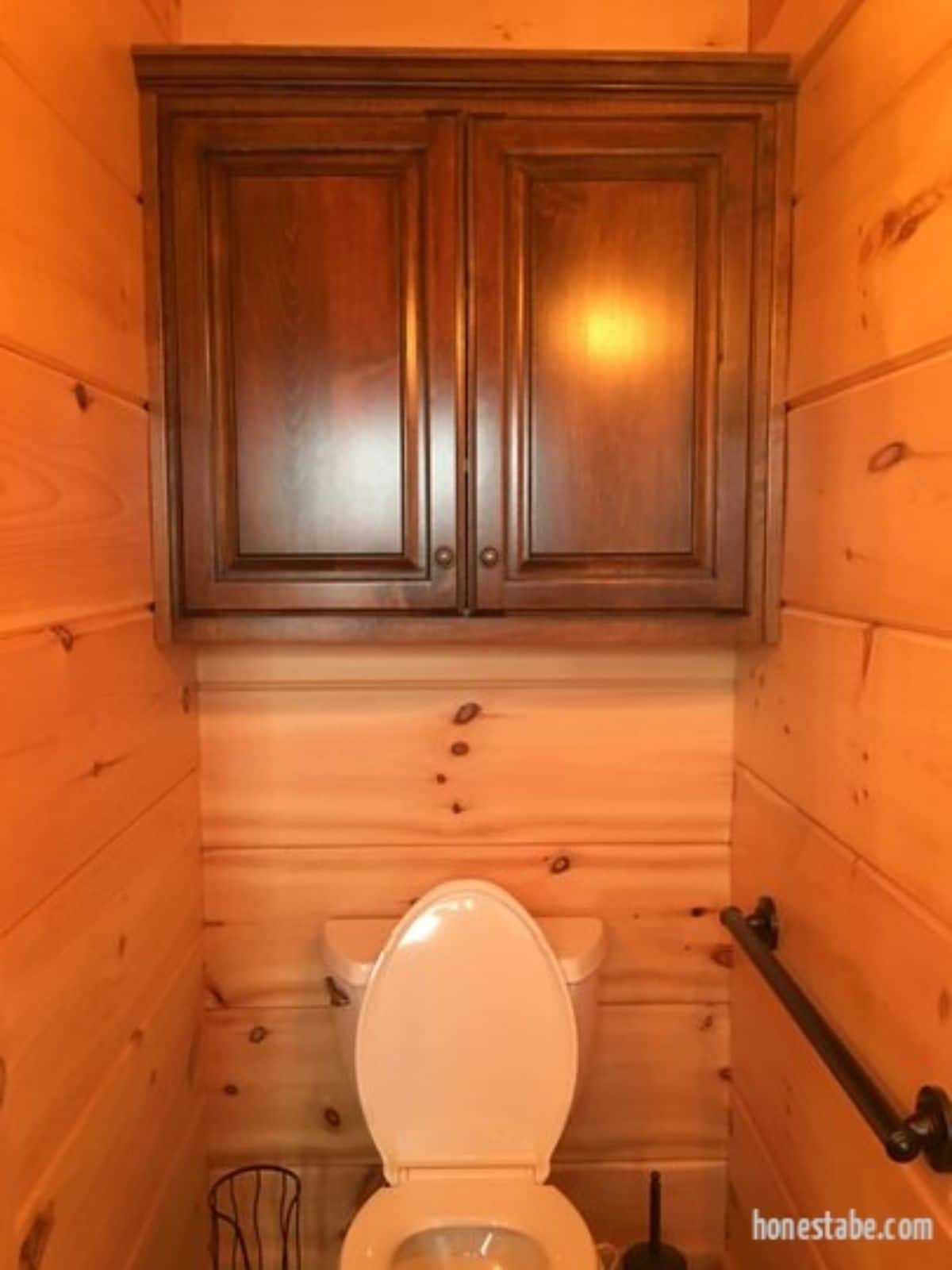 dark wood cabinets on wall above white flush toilet