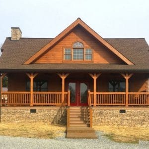 front of log cabin with stone foundation and covered porch