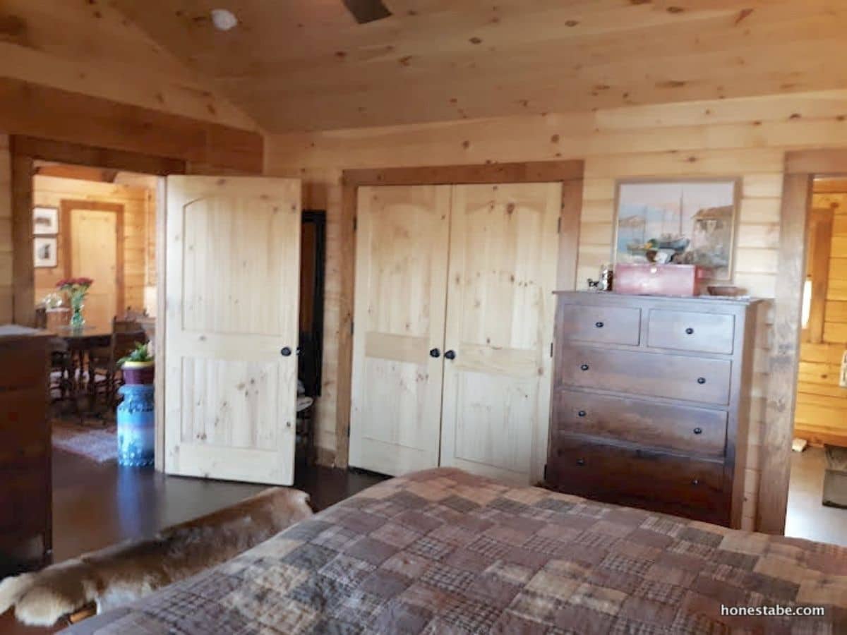 light wood closet doors next to chest of drawers in bedroom with open door