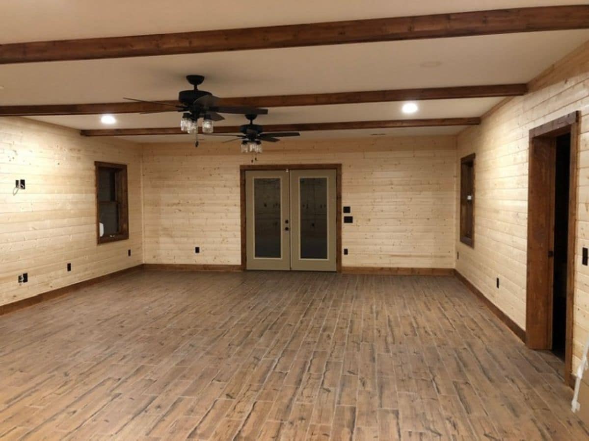 large open space in basement of log cabin with french doors at end of room