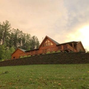 log cabin at top of hill with dark stone retaining wall