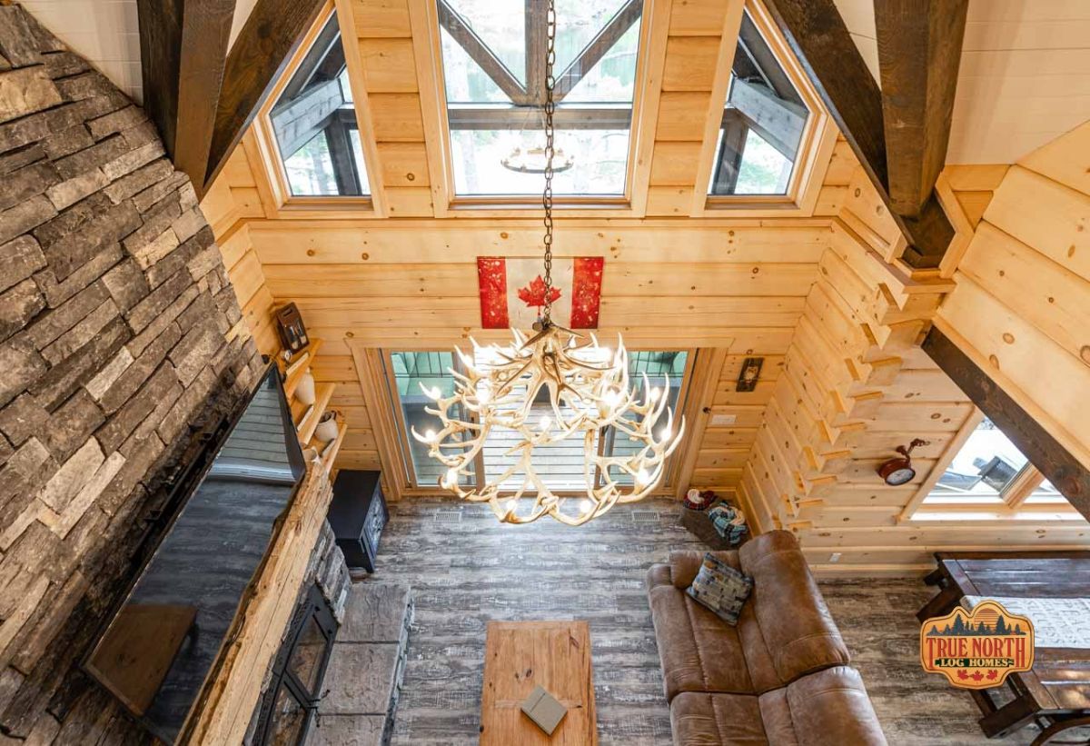 view from loft into living room of log cabin with antler chandelier in center of ceiling