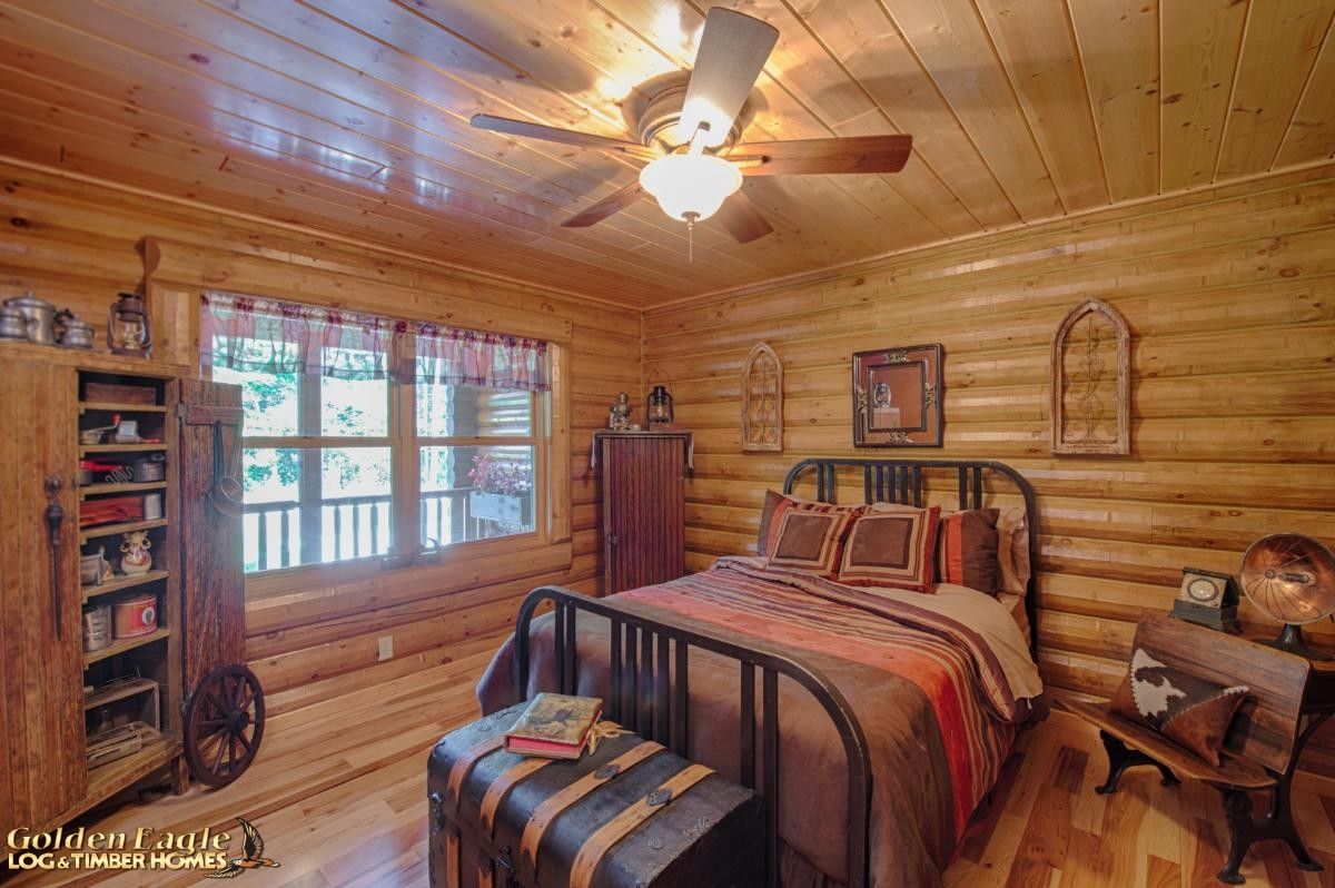 metal bedfame on bed with quilt in log cabin bedroom with ceiling fan