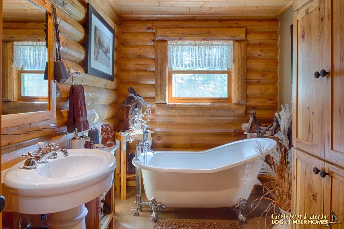 clawfoot soakin gbathtub in log bathroom with pedestal sink against left wall