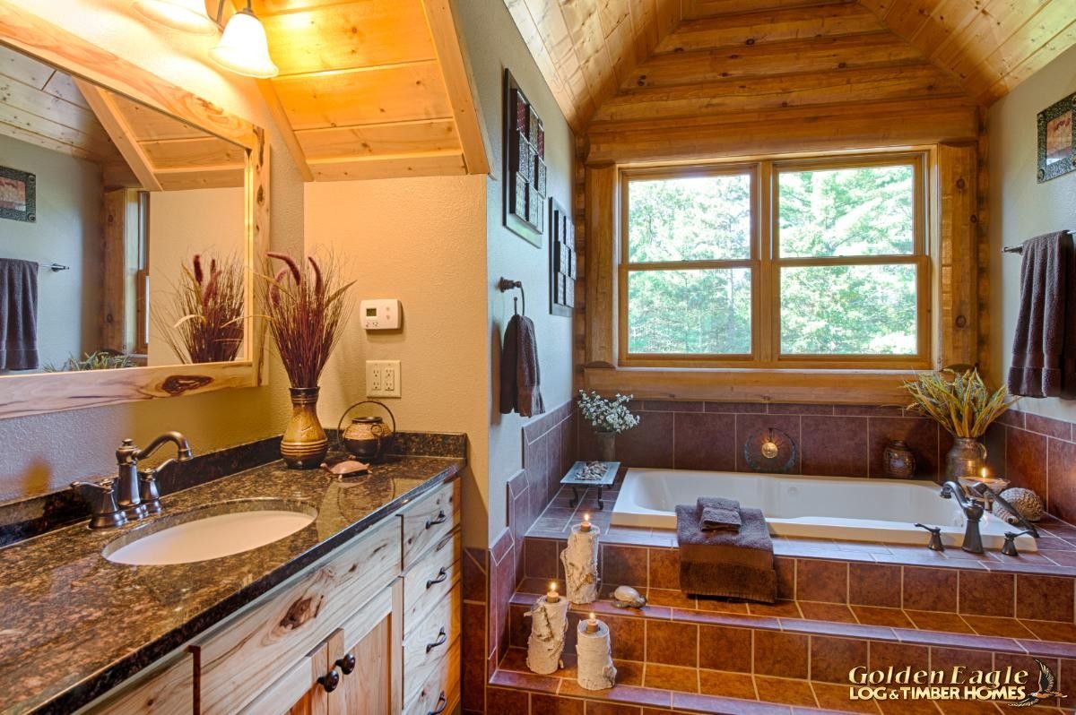 soaking tub with tile surround underneath window in log cabin bathroom