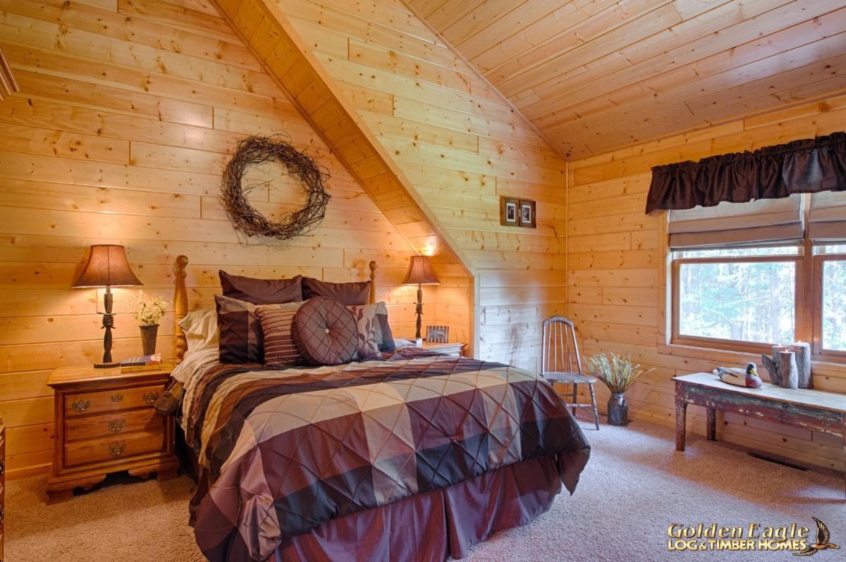 dark maroon and brown duvet on bed against wall in second floor log bedroom