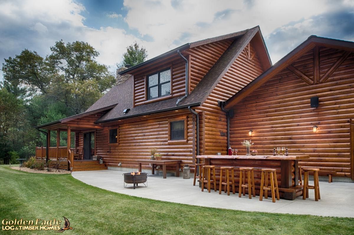 back of log cabin with outside kitchen on concrete walkway