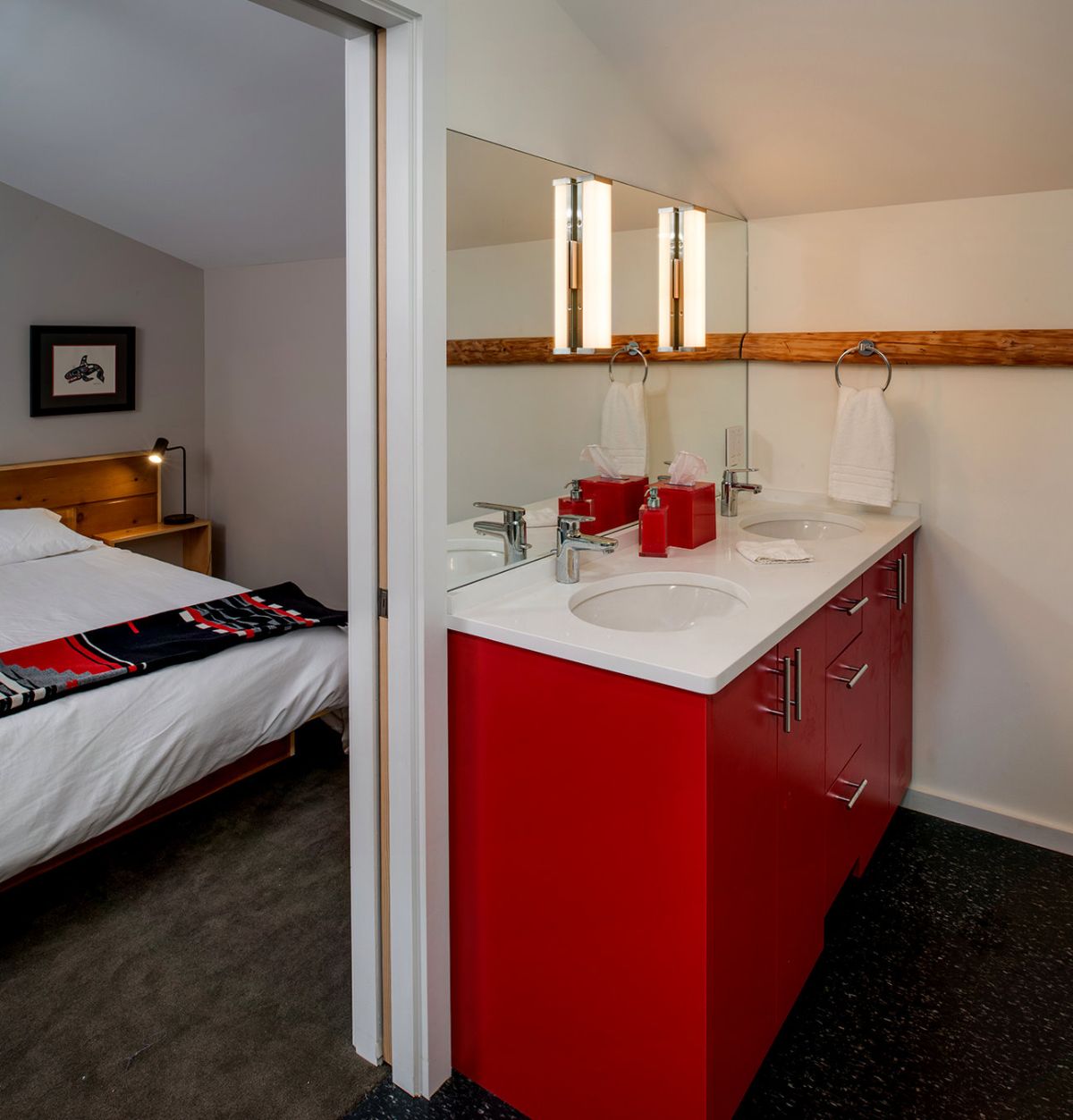 bright red cabinet in bathroom across from bed with black and white blanket