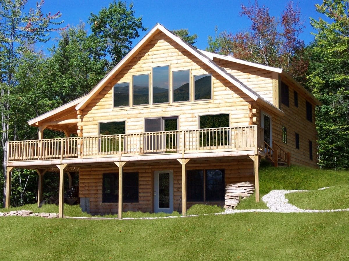 light wood log cabin with walk out basement on grassy hill