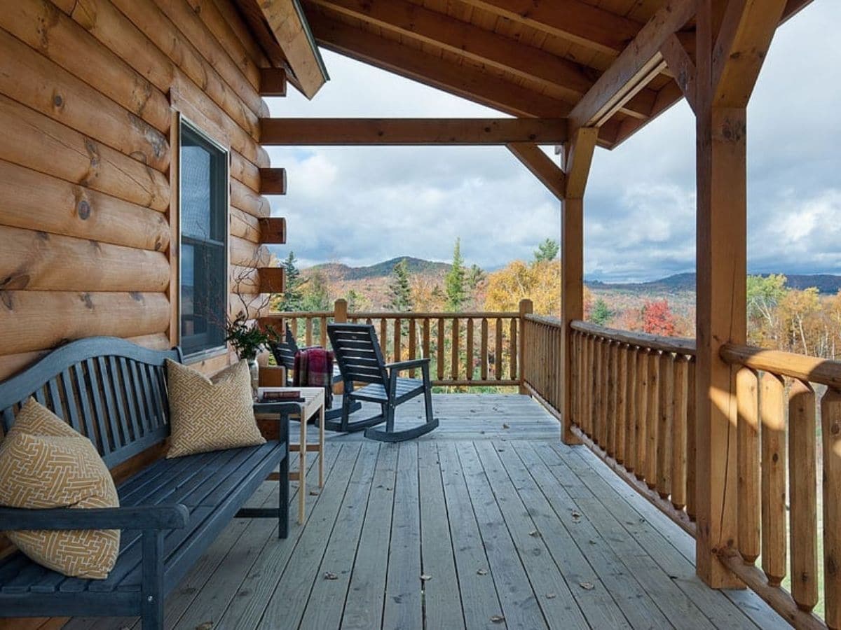 porch with green bench and rocking chairs on log cabin