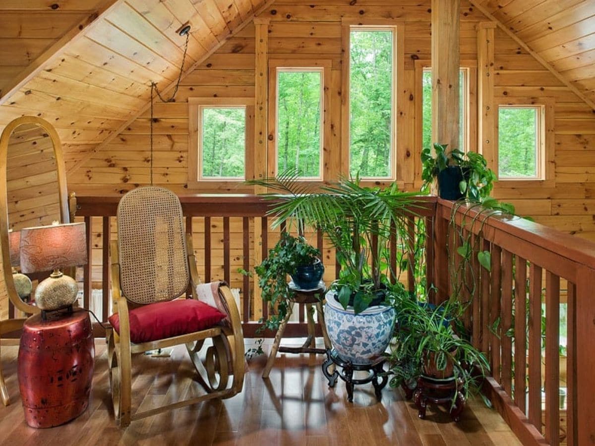 rocking chair on loft balcony overlooking great room with large windows against wall