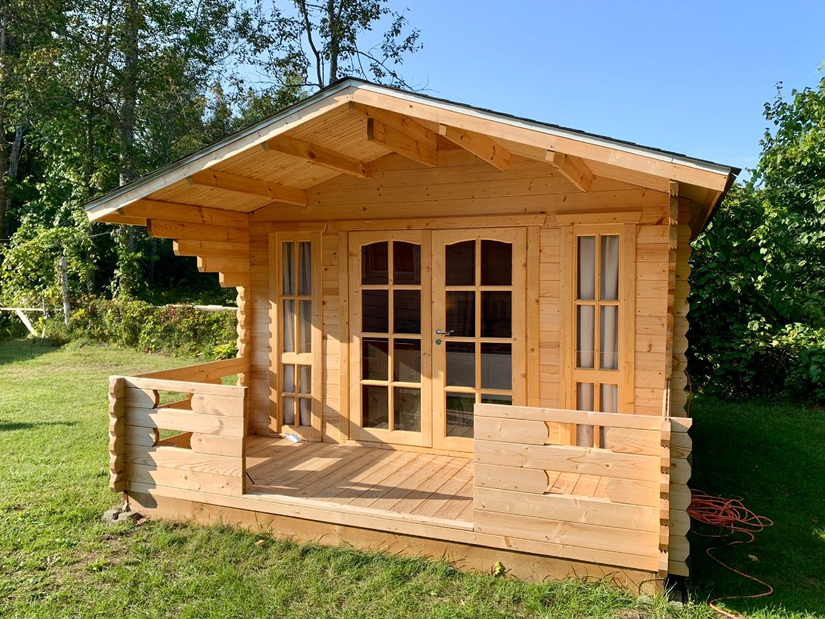 blonde wood tiny log cabin with open porch and glass paneled doors