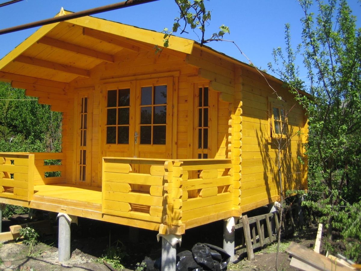 small cabin with porch painted yellow