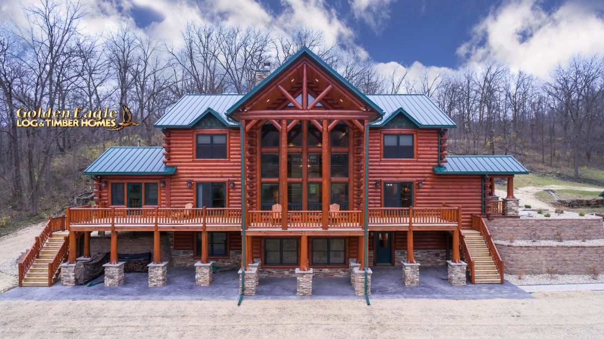 Dark wood log cabin with green roof and stone pillars on bottom floor