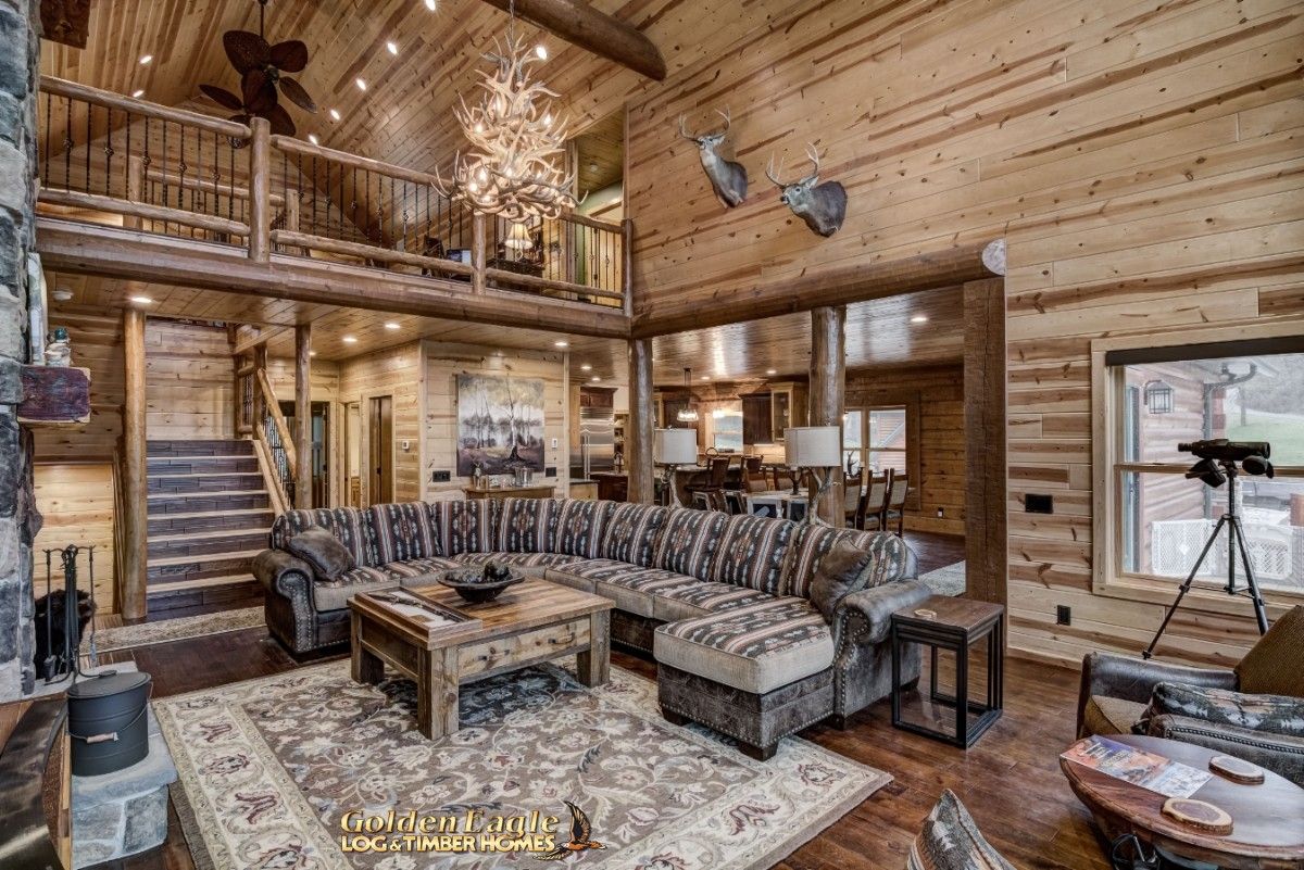 living room with sectional in middle of space and kitchen and loft visible in background