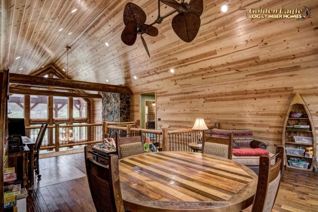 round wood table in loft beneath leaf ceiling fan