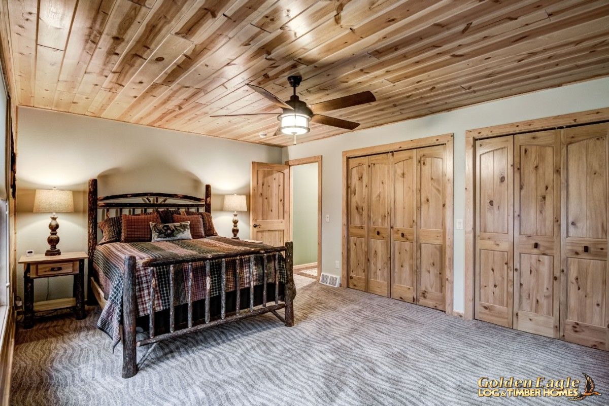 rustic log bed against white wall with light wood doors along wall