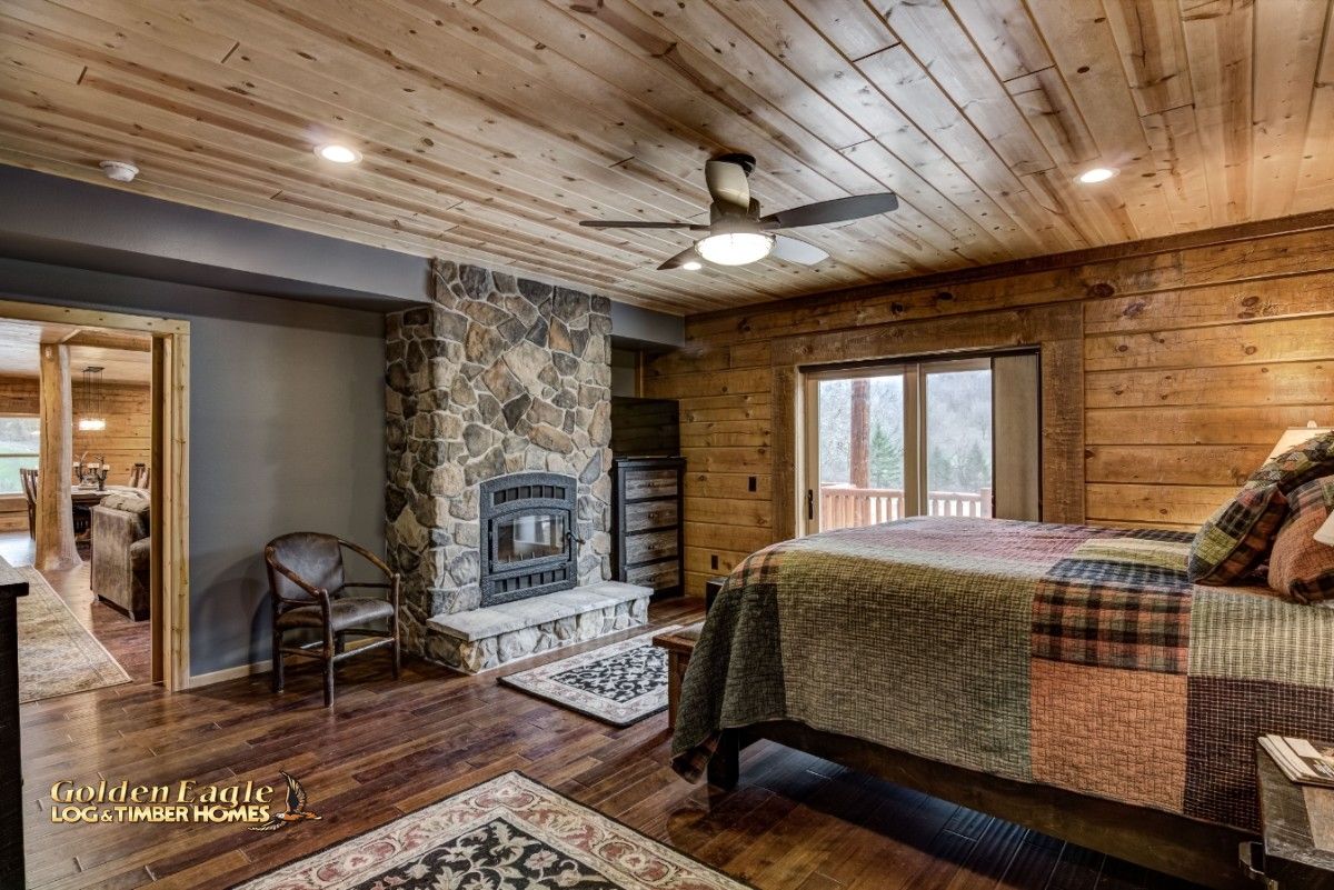 master bedroom with bed on right and fireplace against wall next to balcony doors