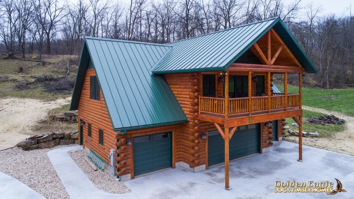 green garage doors on back side of log cabin with green slopign roofline