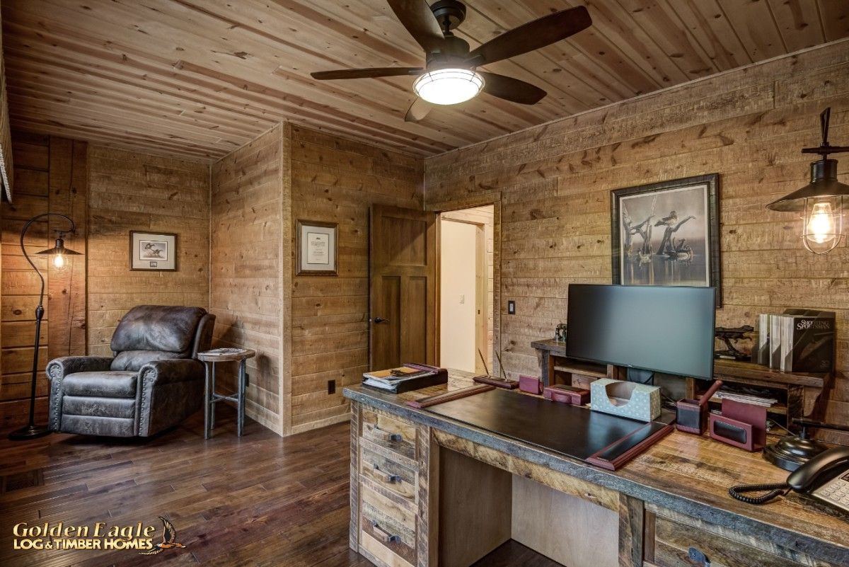 wood desk with large monitor against wall and recliner on left side