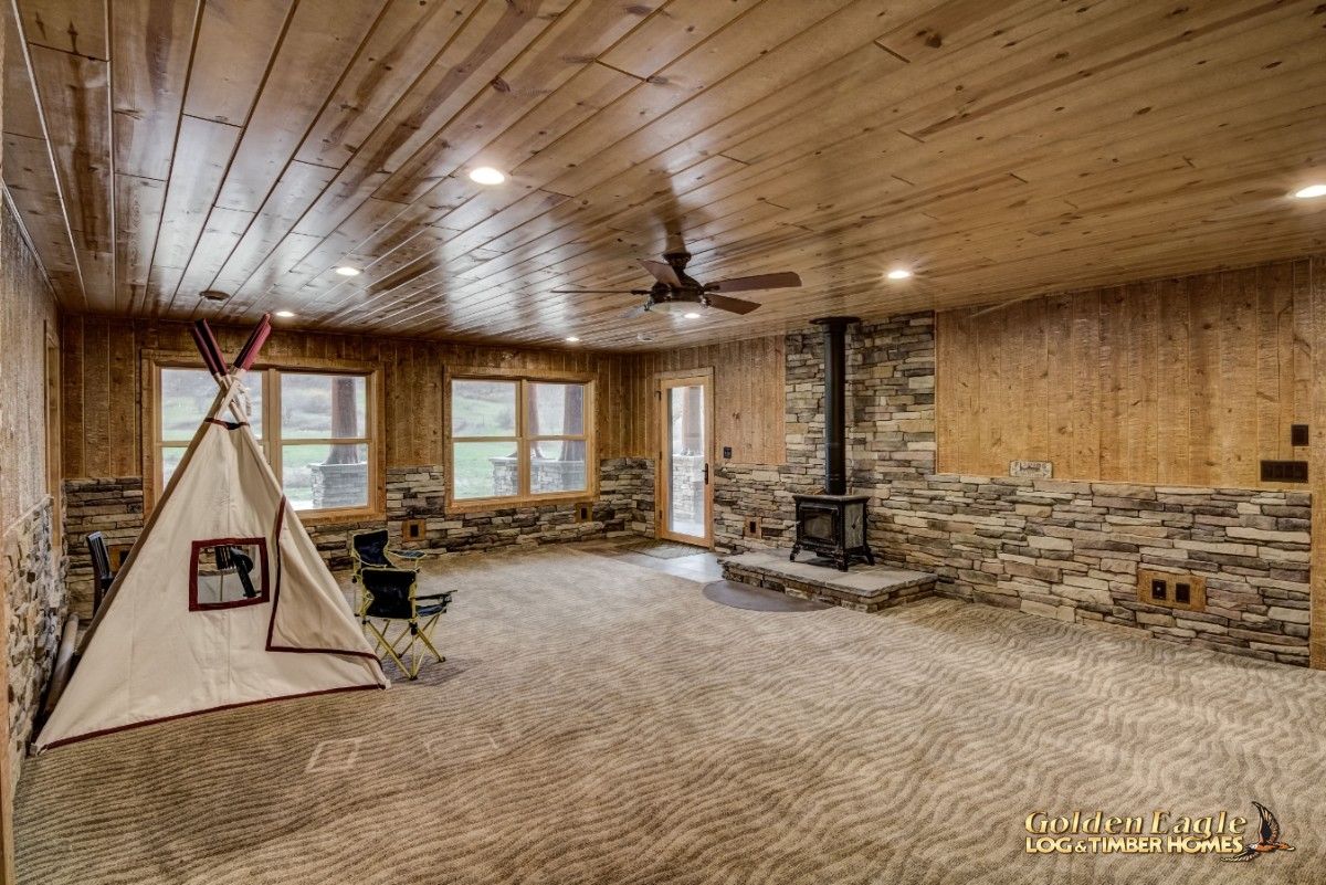 walkout basement with stone backing behind wood stove and teepee on left wall