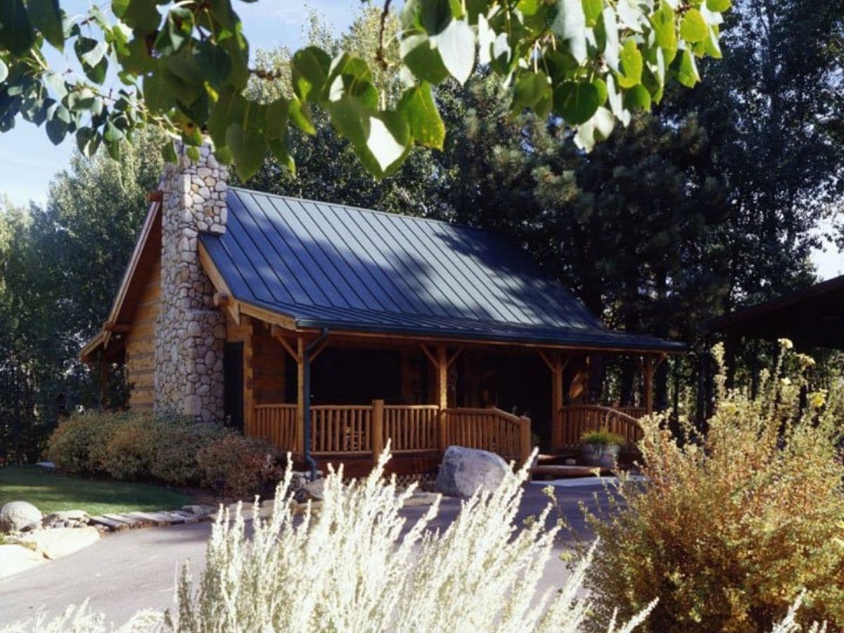 log cabin with stone fireplace on end behind shrubs
