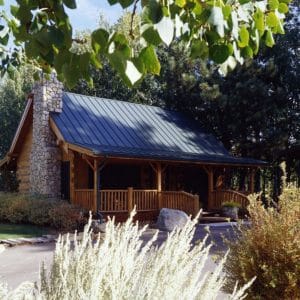 log cabin with stone fireplace on end behind shrubs