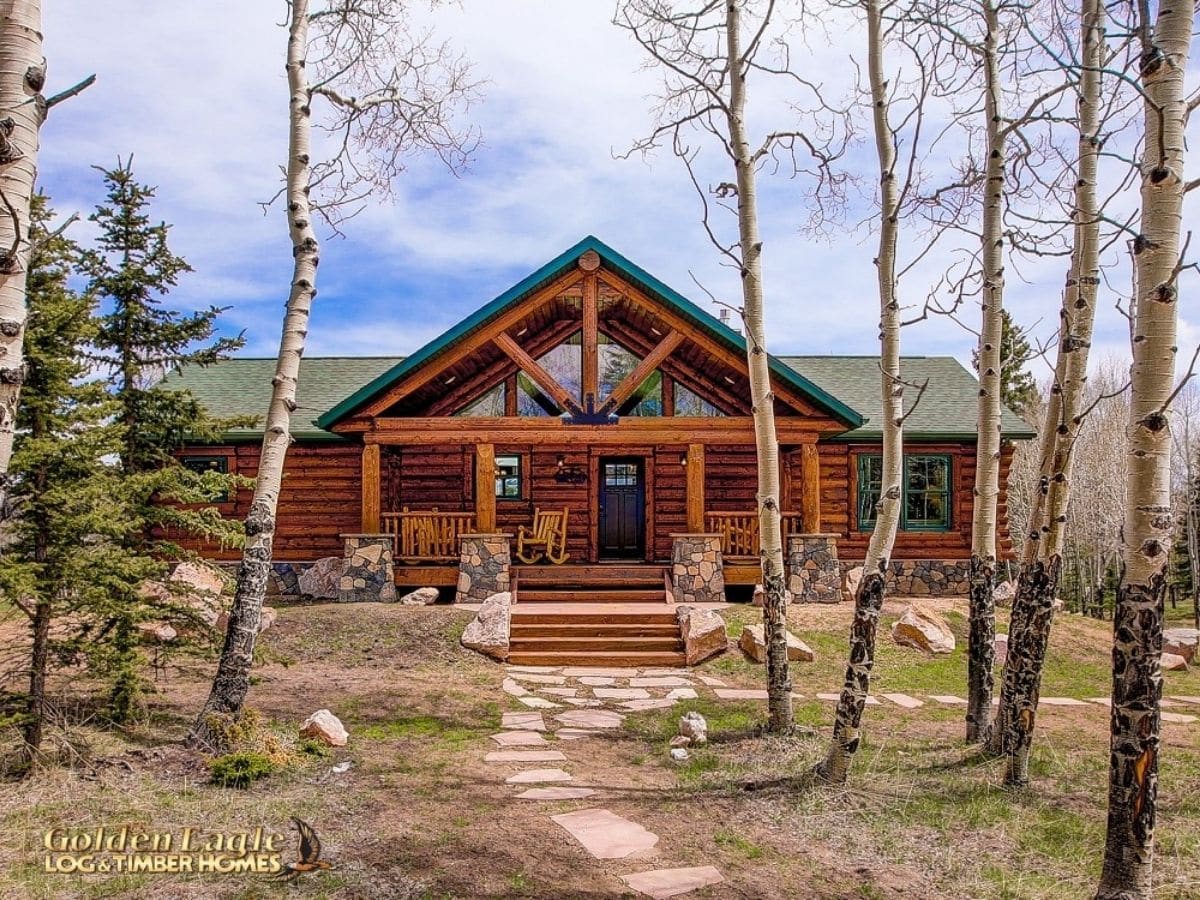 log cabin behind trees with green roof