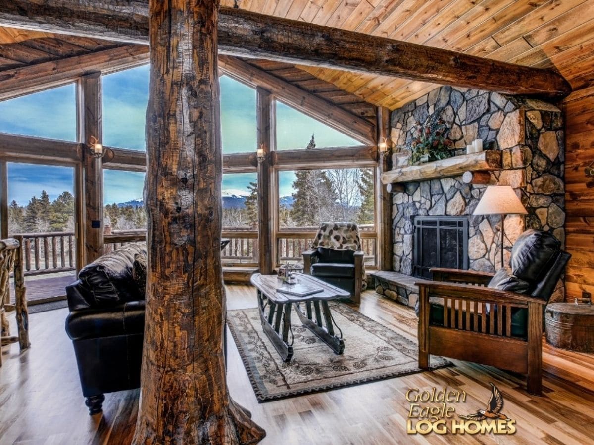 view into great room with stone fireplace on right and log column in foreground