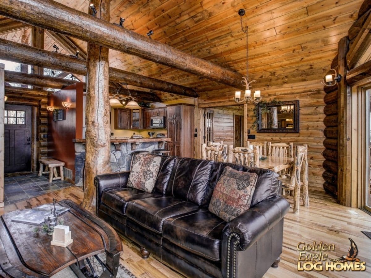 black leather sofa in front of kitchen of log cabin