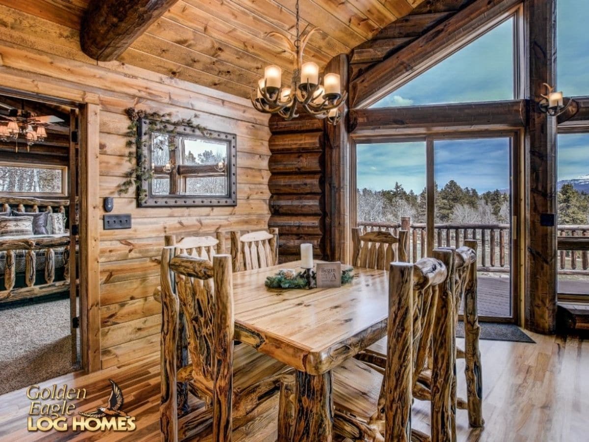 square wooden table in log cabin by large window